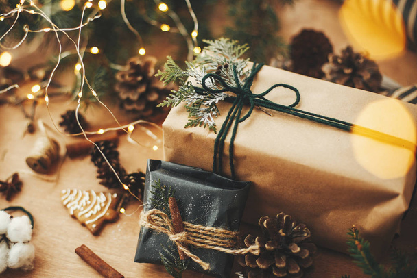 Κομψά ρουστίκ χριστουγεννιάτικα δώρα με κλαδιά κέδρου και κανέλα  - Φωτογραφία, εικόνα