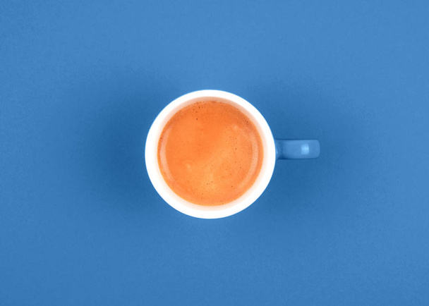 Top view of fresh brewed coffee in ceramic cup on blue background. - Photo, Image