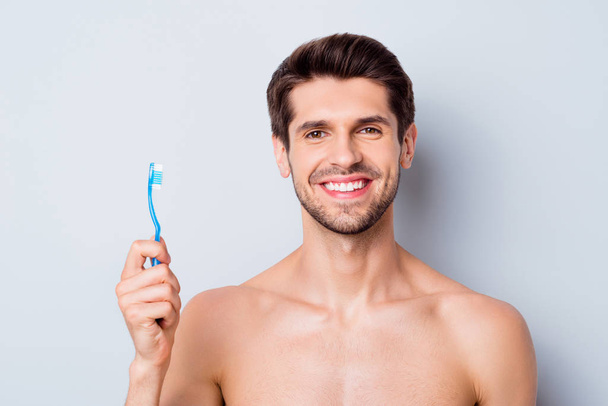 Close-up portrait of his he nice attractive bearded cheerful brown-haired nude guy holding in hand toothbrush perfection enhancement gum therapy isolated on light white grey color pastel background - Fotó, kép