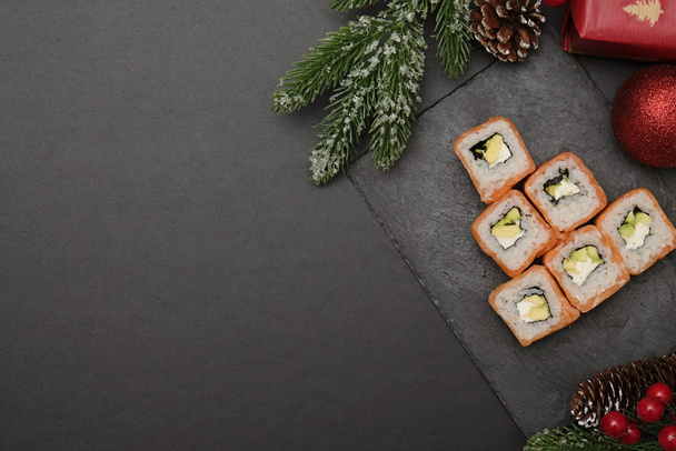 Sushi for christmas concept. Edible christmas tree mde from Philadelphia roll on black background. Food for christmas eve. - Фото, изображение