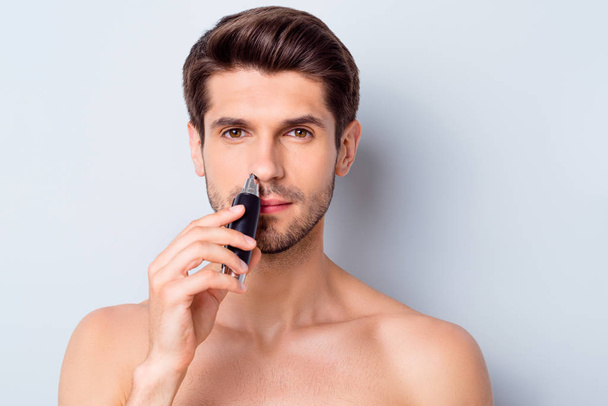 Photo of handsome macho man guy looking mirror using electric battery trimmer get rid of nose hair topless tender torso metrosexual body isolated grey background - Photo, Image