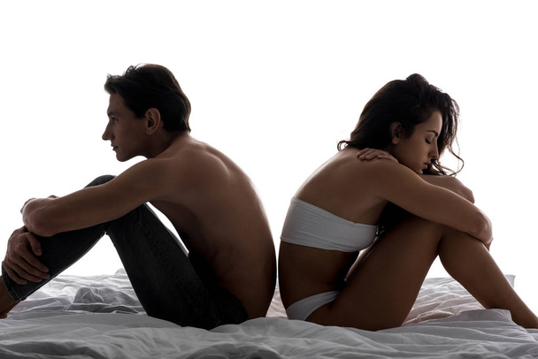 beautiful offended couple sitting back to back on white bed - Photo, Image