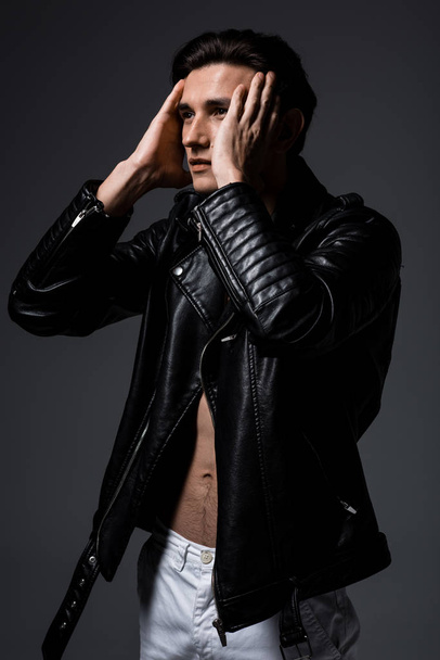 young sexy man in black leather jacket, isolated on grey - Photo, Image