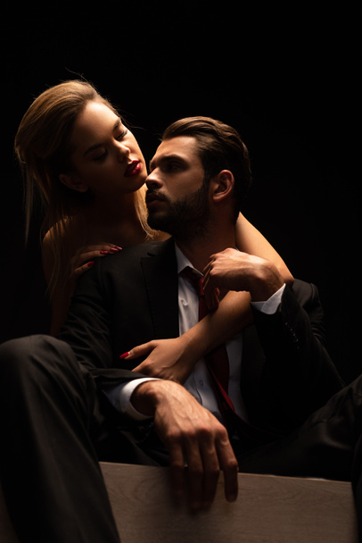 beautiful elegant passionate couple sitting on bed in dark room - Foto, Imagem