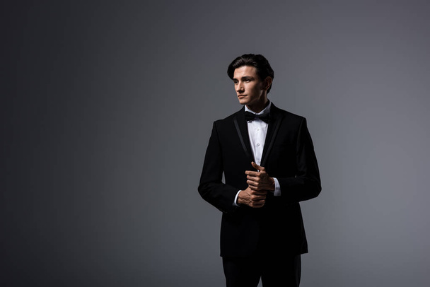 hombre guapo en traje negro y lazo de corbata, aislado en gris
 - Foto, Imagen