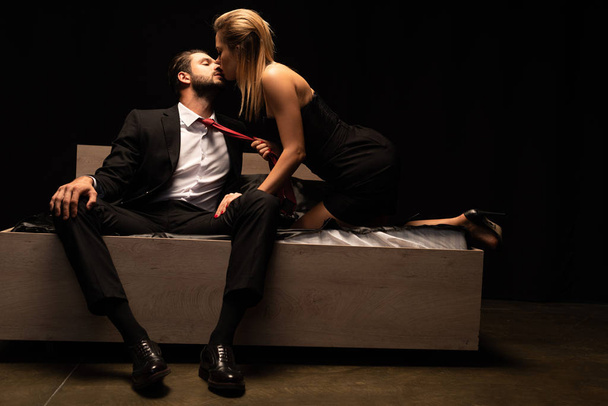beautiful seductive couple of lovers sitting on bed in dark room - Photo, Image