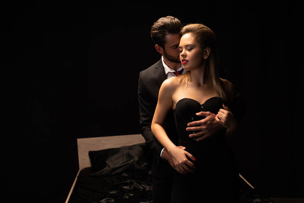 passionate couple standing near bed in dark room - Foto, afbeelding