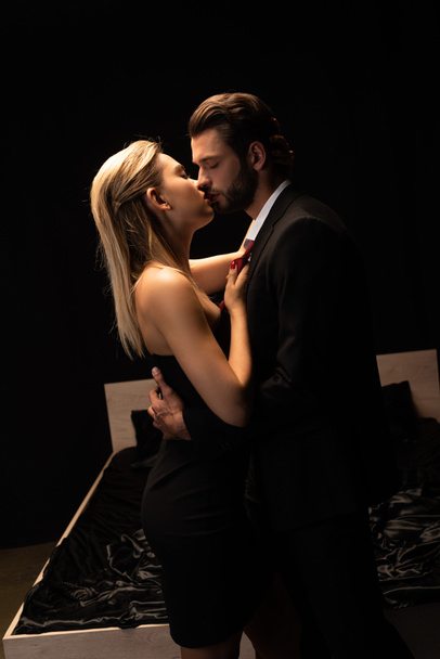 beau couple sexy élégant embrasser près du lit dans la chambre noire
 - Photo, image