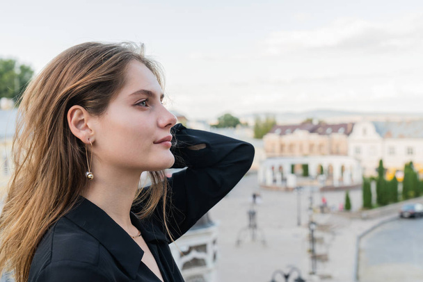 Side view portrait of attractive brunette girl with loose hair and natural makeup, old city on the background - Fotografie, Obrázek