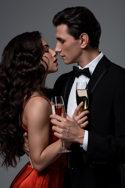 Couple romantique tenant des verres à champagne et allant embrasser, isolé sur gris
 - Photo, image