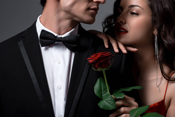 Romantikus pár ölelés és gazdaság vörös rózsa virág elszigetelt szürke - Fotó, kép