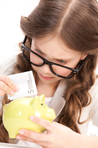 Little girl with piggy bank and money - Zdjęcie, obraz