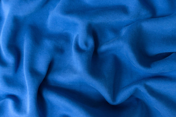 Μπλε υφασμάτινο φόντο. Υφασμάτινο ύφασμα χρωματισμένο σε κλασικό μπλε χρώμα της μόδας του έτους 2020. Κλασικό μπλε χρώμα Pantone. Ρηχό βάθος πεδίου, επιλεκτική εστίαση - Φωτογραφία, εικόνα