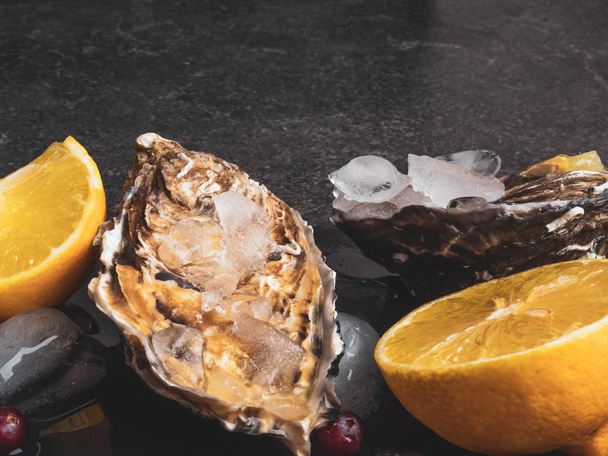 čerstvé ústřice v kamenné břidlici s ledem, brusinkami, citronovými plátky, lahůdkami drahé jídlo, bohaté na zinek, antioxidanty, vitamíny - Fotografie, Obrázek