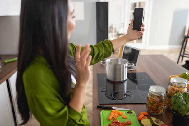 Housewife with a smartphone in the kitchen - 写真・画像