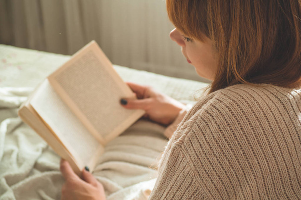 Atrakcyjna młoda kobieta czyta książkę w domu. Przemyślana dziewczyna czytająca ważną książkę. - Zdjęcie, obraz