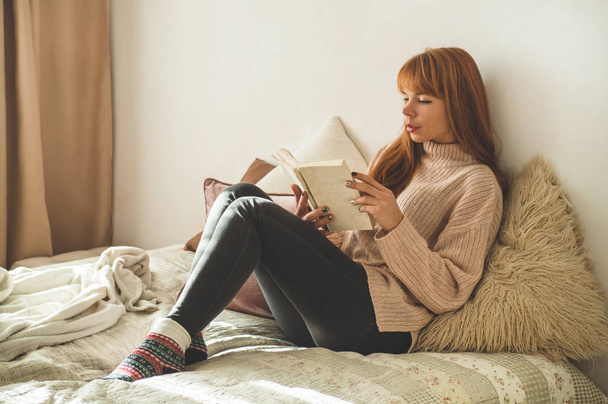 Aantrekkelijke jonge vrouw leest thuis een boek. Bedachtzaam meisje het lezen van belangrijke boek. - Foto, afbeelding