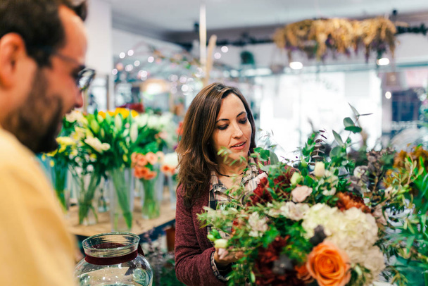 junge Frau kauft einen Blumenstrauß im Blumenladen - Foto, Bild