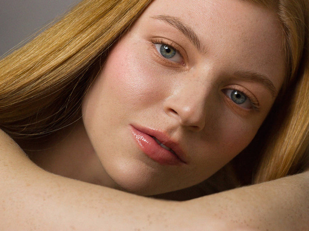 Freckles Woman portrait. Close-up. A beautiful gray-eyed girl with freckles is looking at the camera, on white background. Skin care. The beauty of red straight hair. Beautiful nude makeup. Pink lips - Photo, image