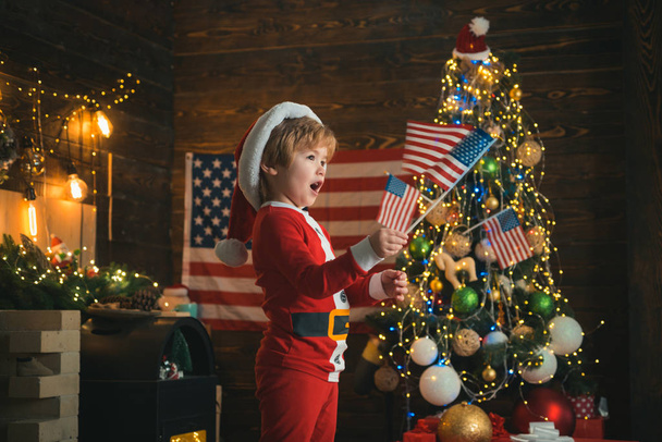 Boldog karácsonyt Amerikában. Karácsonyi gyerek amerikai zászlókkal. Karácsony az Egyesült Államokban. - Fotó, kép