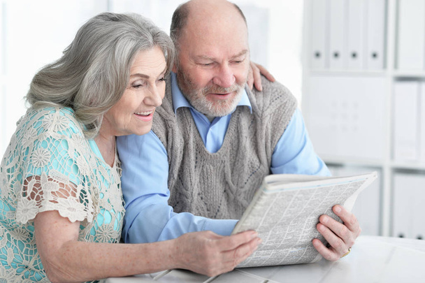 Close-up portrait of a  senior couple with newspaper  at home  - Fotó, kép