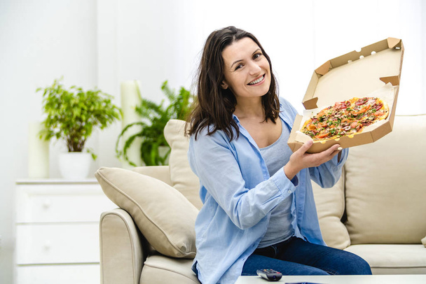 Beautiful and happy woman is eating pizza. She is smiling sincerely. Copy space. Close up. - Foto, Bild