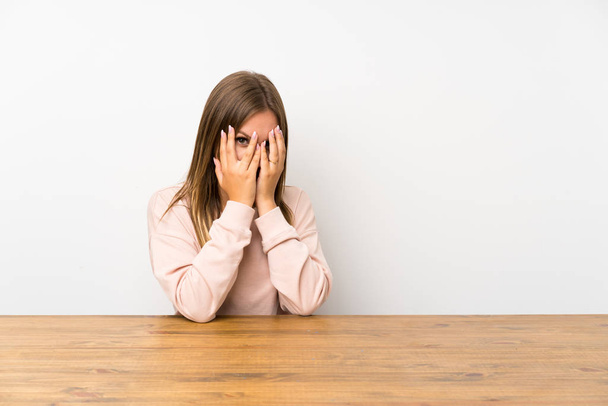 Teenager dívka v tabulce zakrývající oči a dívá se skrz prsty - Fotografie, Obrázek