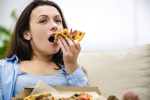 Satisfied and happy woman enjoys eating pizza. Close up. Copy space. - Фото, зображення