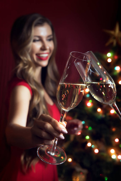 portrait of nice woman in red dress with champagne  in christmas environment - 写真・画像