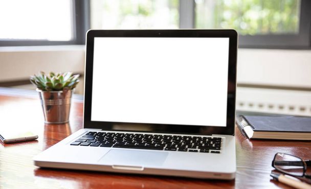 Portátil con pantalla blanca en blanco en un escritorio de madera
 - Foto, imagen