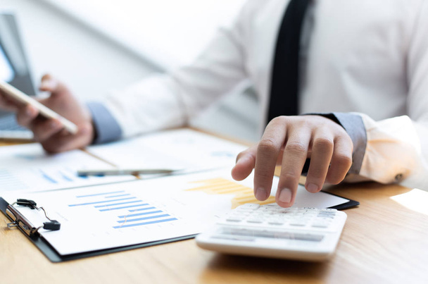 Gli uomini d'affari utilizzano calcolatori per calcolare le imposte e le entrate della società in ufficio, concetti bancari finanziari e contabili
. - Foto, immagini