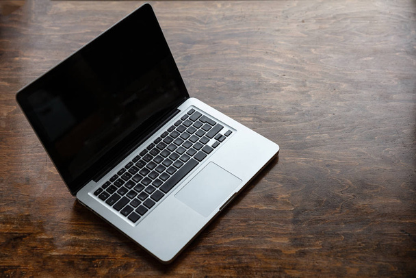 Laptop with black blank screen on a wooden desk - Fotó, kép