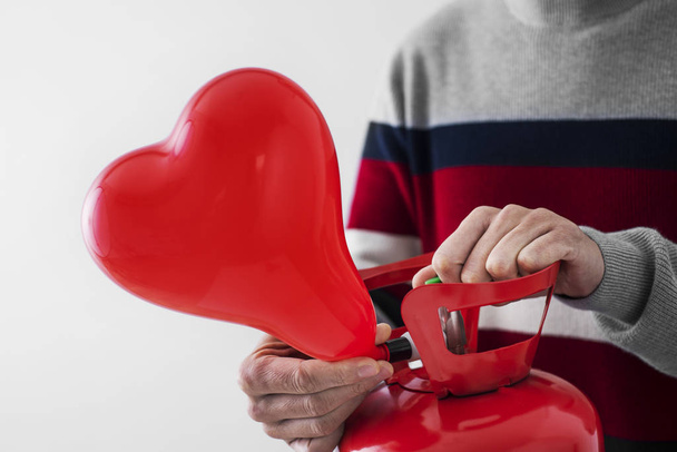 φουσκώνοντας ένα μπαλόνι σε σχήμα καρδιάς από έναν κύλινδρο - Φωτογραφία, εικόνα