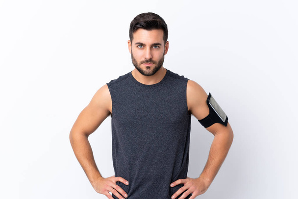 Young sport handsome man with beard over isolated white background posing with arms at hip - Foto, imagen
