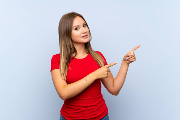 Teenager girl over isolated blue background pointing finger to the side - Photo, Image