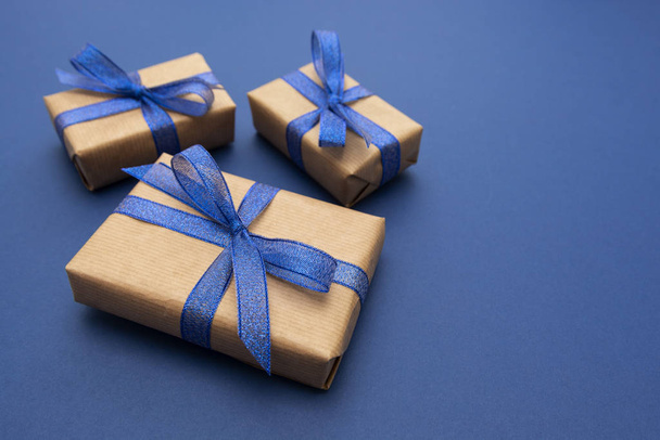 Christmas or birthday presents. Craft paper wrapped gift boxes on blue background, flat lay. Copy space. - Foto, afbeelding