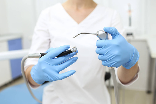 Closeup of dentist tools in hands of womn in blue glowes. Selective focus - Foto, imagen