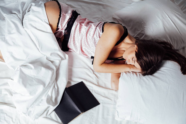 girl in pajamas lying on the bed with a book before bed - Fotoğraf, Görsel
