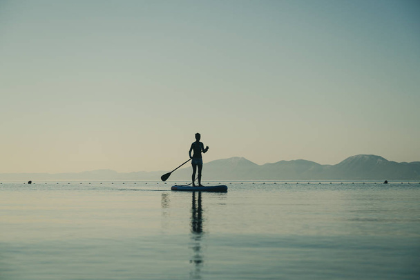 Jonge vrouw op stand up paddle board - Foto, afbeelding