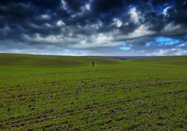 homme sur le terrain. nuages pittoresques sur un champ vallonné
 - Photo, image