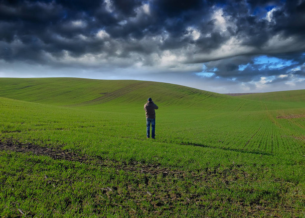 homme sur le terrain. nuages pittoresques sur un champ vallonné
 - Photo, image