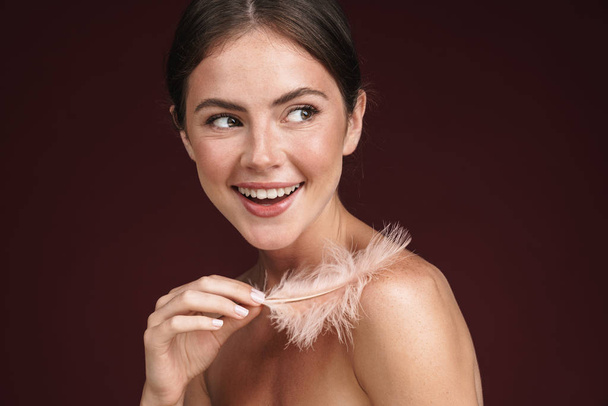 Image of delighted half-naked woman holding feather and looking aside - Φωτογραφία, εικόνα