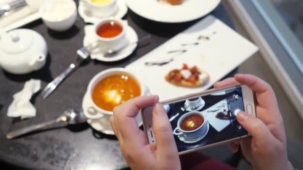 Mujer toma fotos de la comida en el teléfono en un café
 - Metraje, vídeo
