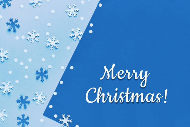 Monochrome blue color toned geometric paper background with text "Merry Christmas". Creative trendy paper craft, flat lay in blue and white with snow. - Foto, afbeelding