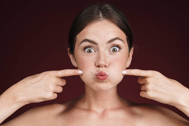 Image of half-naked woman grimacing and pointing fingers at her cheeks - Фото, изображение