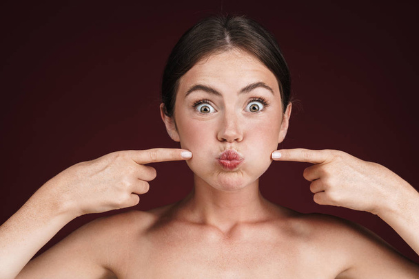 Image of half-naked woman grimacing and pointing fingers at her cheeks - Foto, Imagem