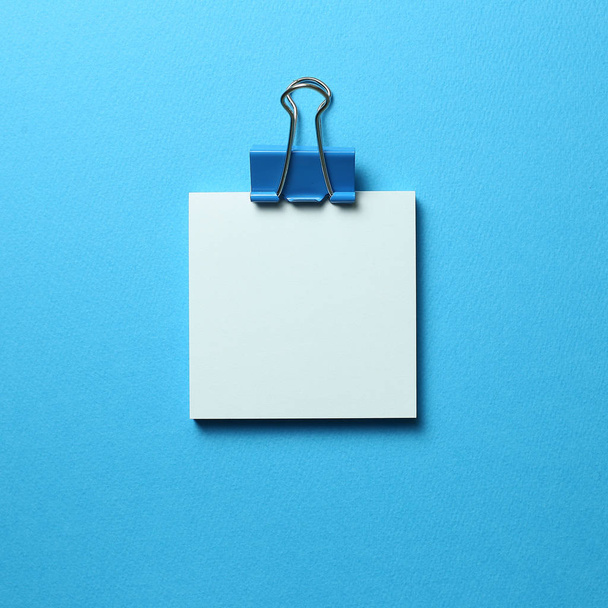 Almohadilla azul nota adhesiva y clip sobre fondo azul
 - Foto, Imagen