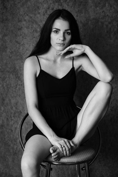 portrait of a charismatic young brunette girl in a dress sitting on a chair - Фото, зображення