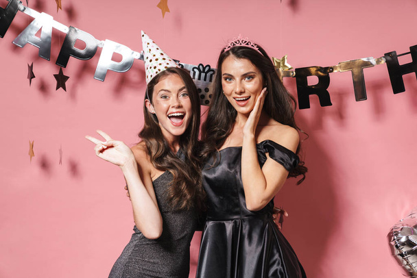 Two cheerful pretty girls wearing dresses celebrating birthday - Zdjęcie, obraz