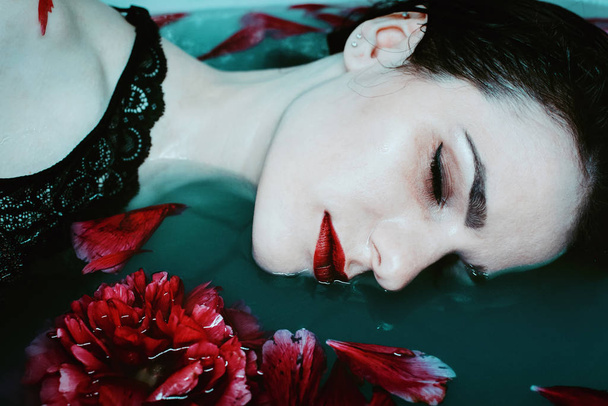 dramatic portrait of a young dead pale girl floating in the water - Foto, afbeelding